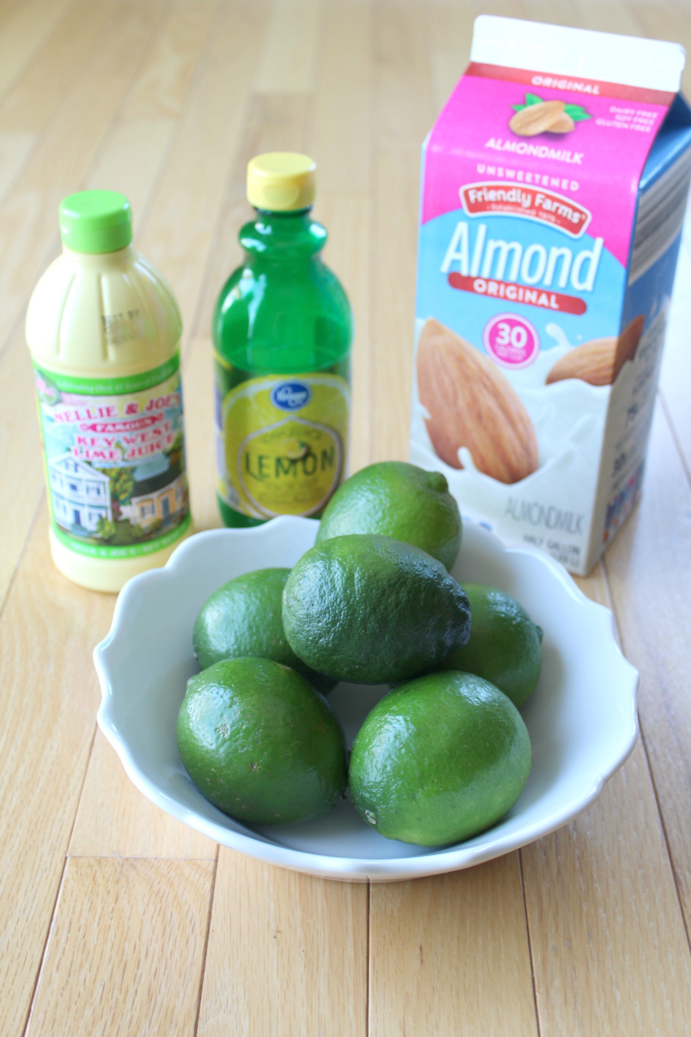 ingredients for lime dole whip with limes, almond milk, lemon juice and lime juice.