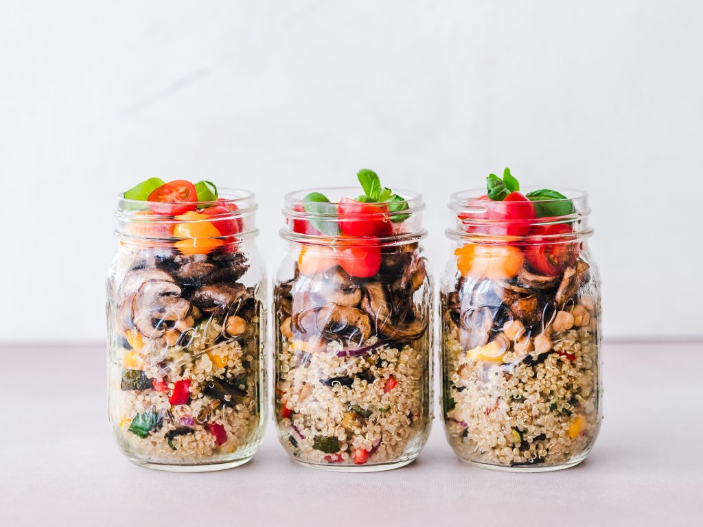 3 mason jars filled with vegetable quinoa, mushrooms and tomatoes with herbs